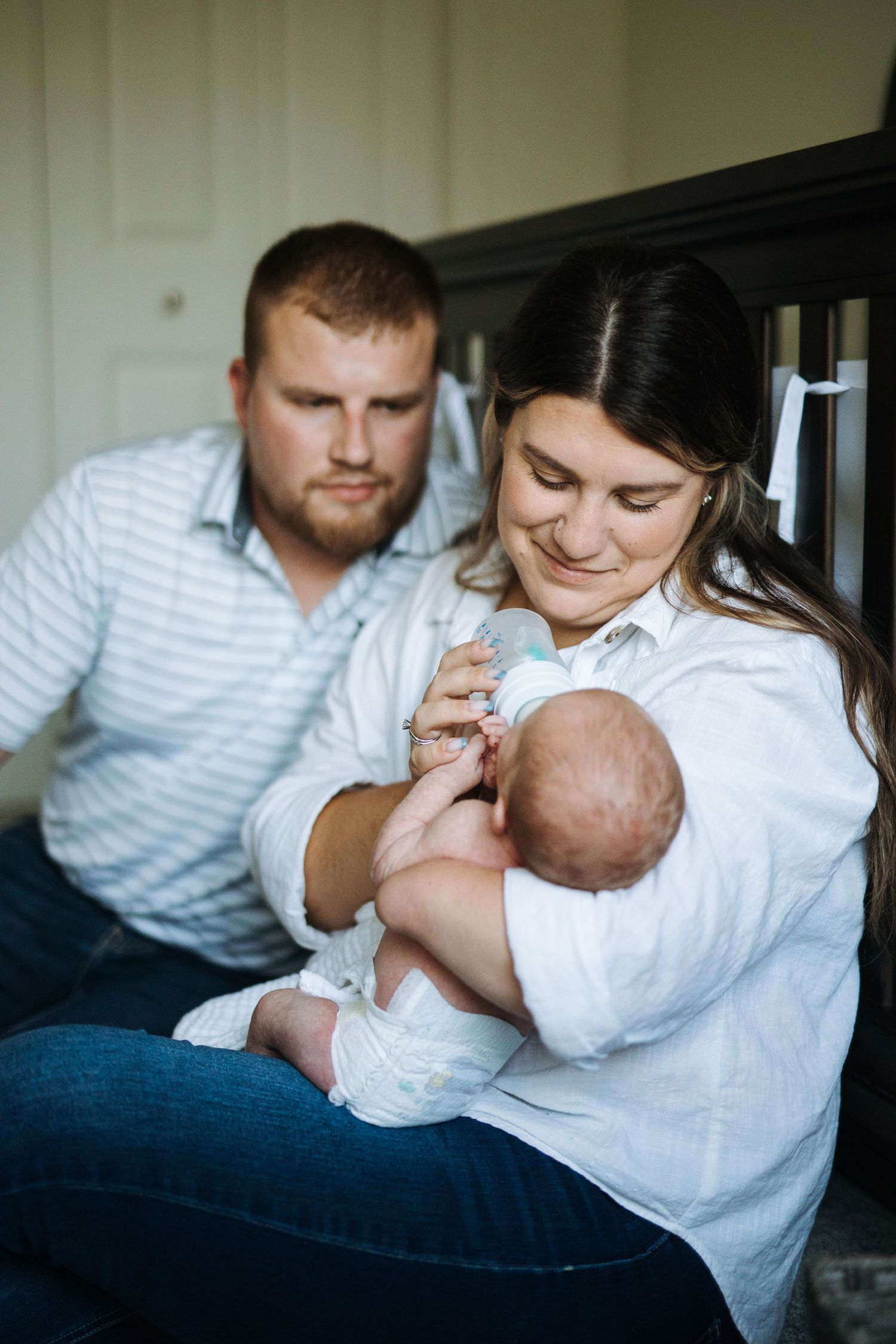 Intimate indoor family portrait with newborn baby in white clothing.