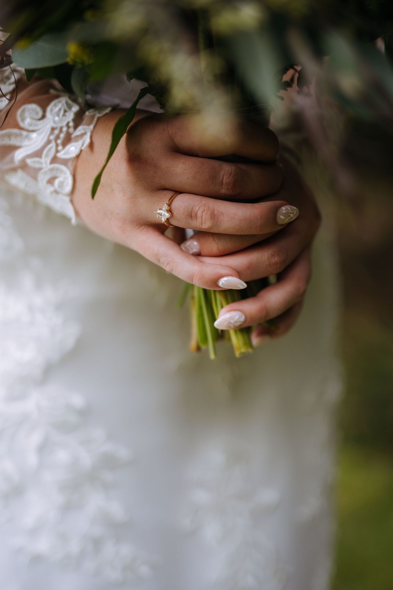 Close-up of hands holding a yellow bouquet against a white wedding dress.