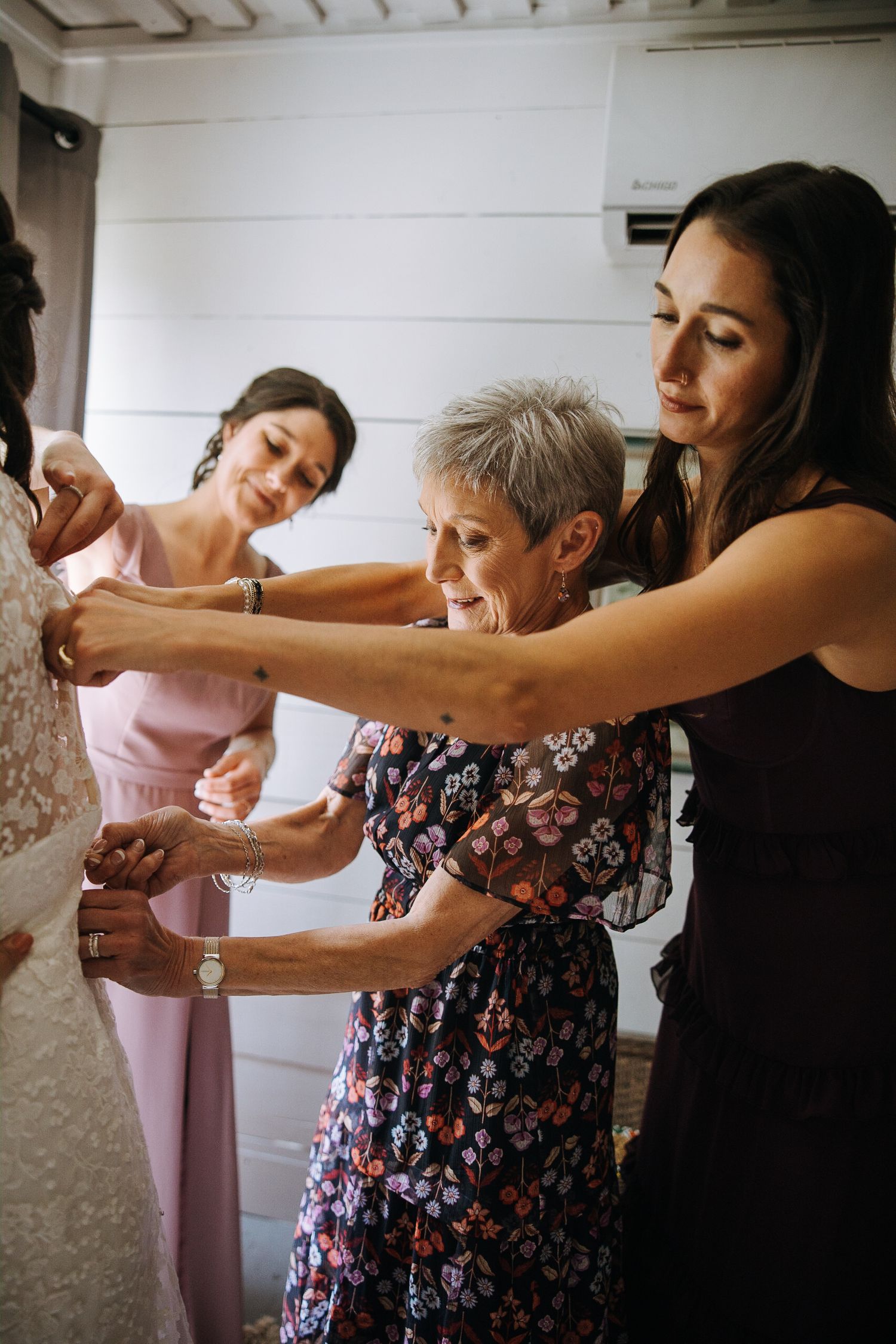 Group of people in floral dresses helping with wedding preparations indoors.