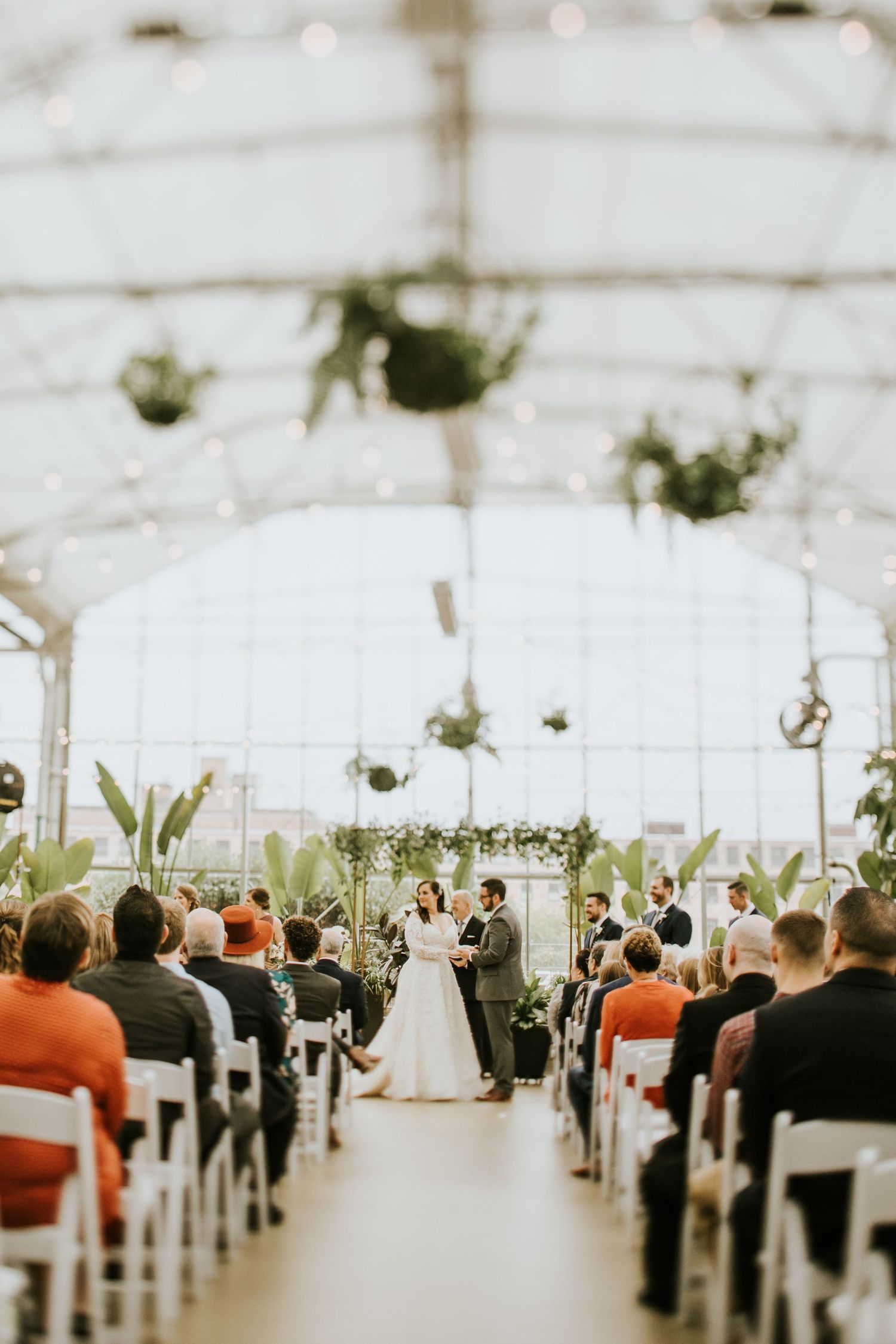 Wedding ceremony in a white tent with guests seated in rows watching couple at the altar.
