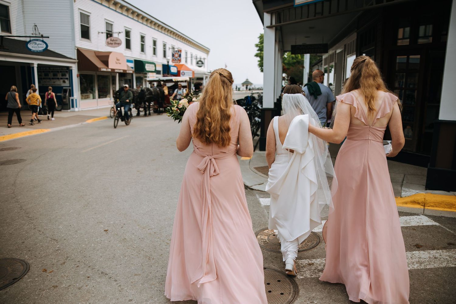 Bridal party walking down a city sidewalk in pink bridesmaid dresses.