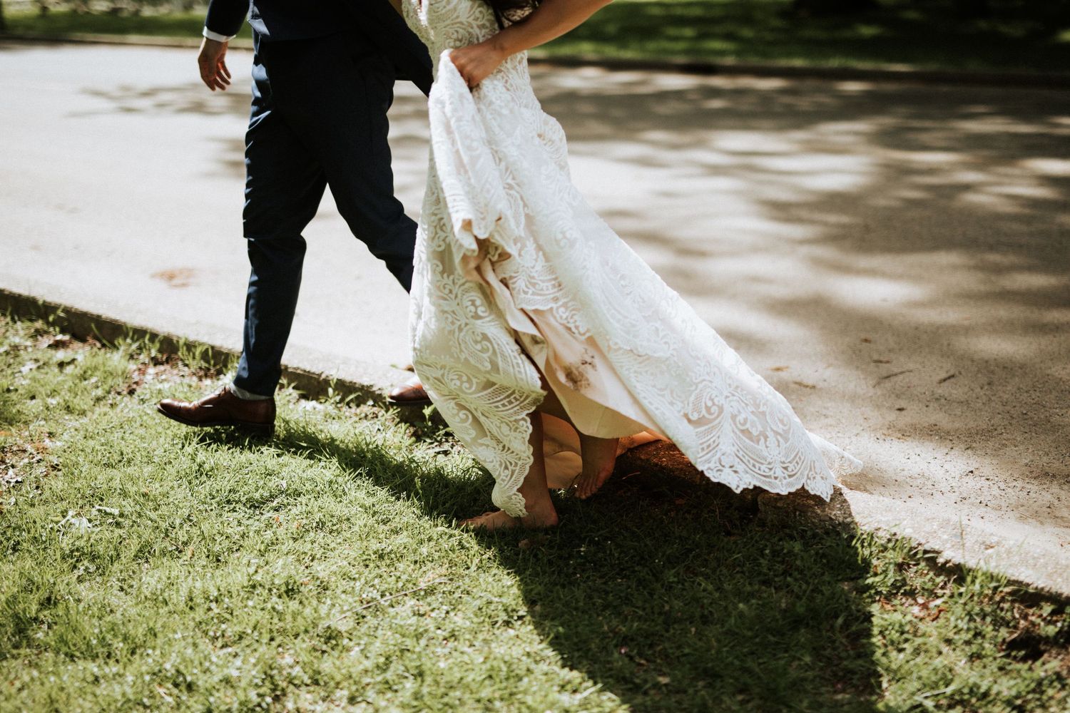 Wedding dress hem and shoes walking along a garden path on a sunny day.