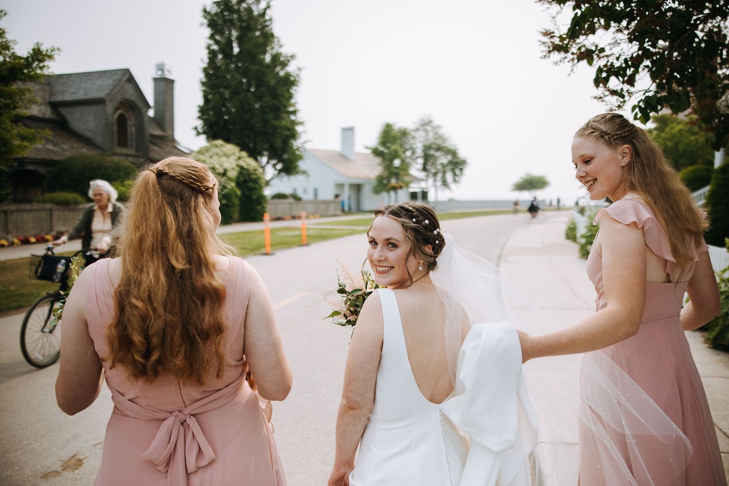 Wedding party in pink dresses walking together outdoors on a sunny day.