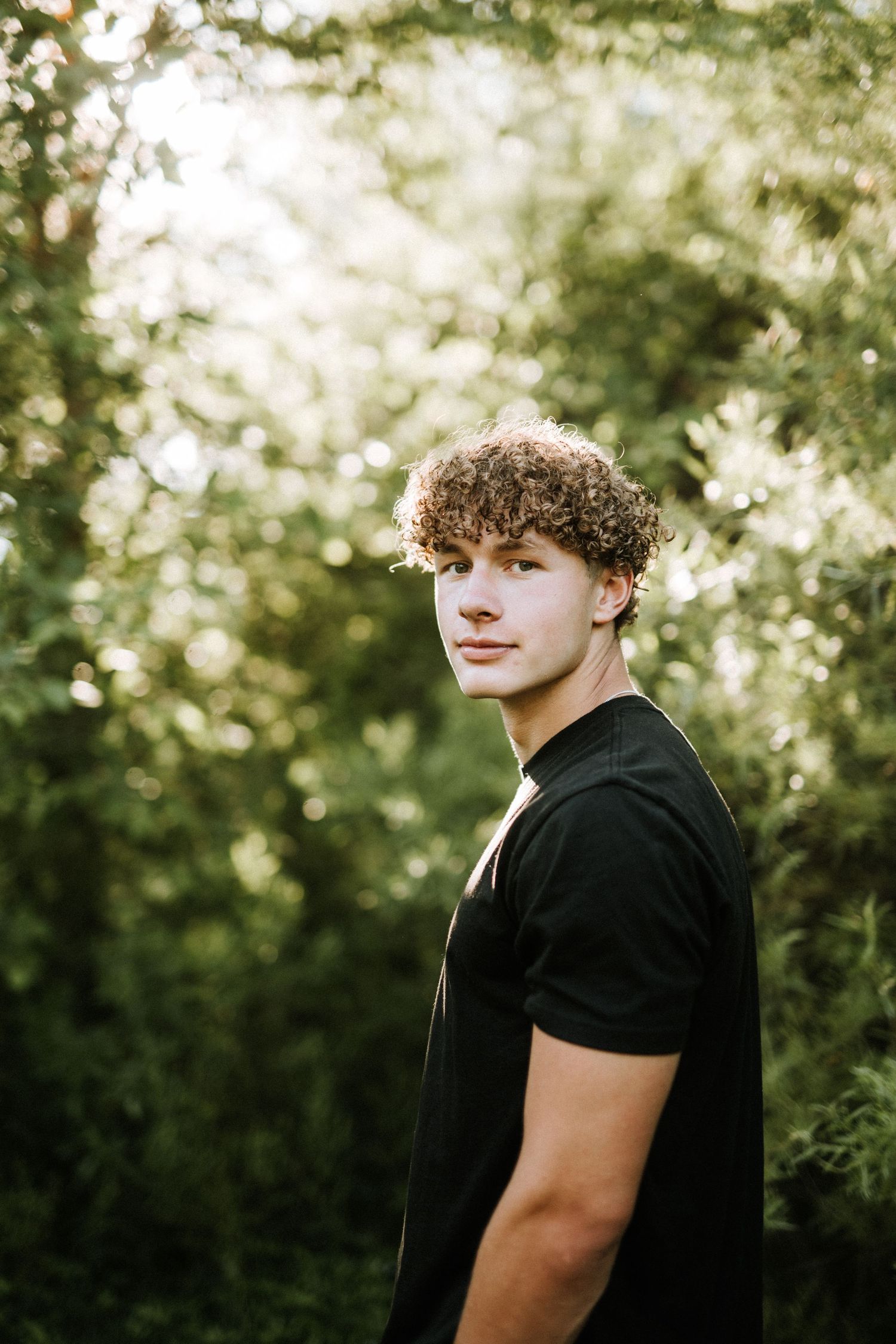 Artistic portrait series showing silhouette against sunlit green foliage background.