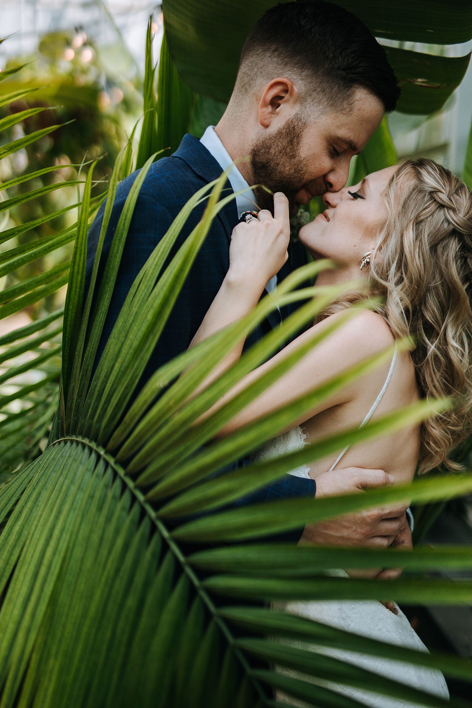 Romantic moment framed by tropical palm leaves in natural lighting.