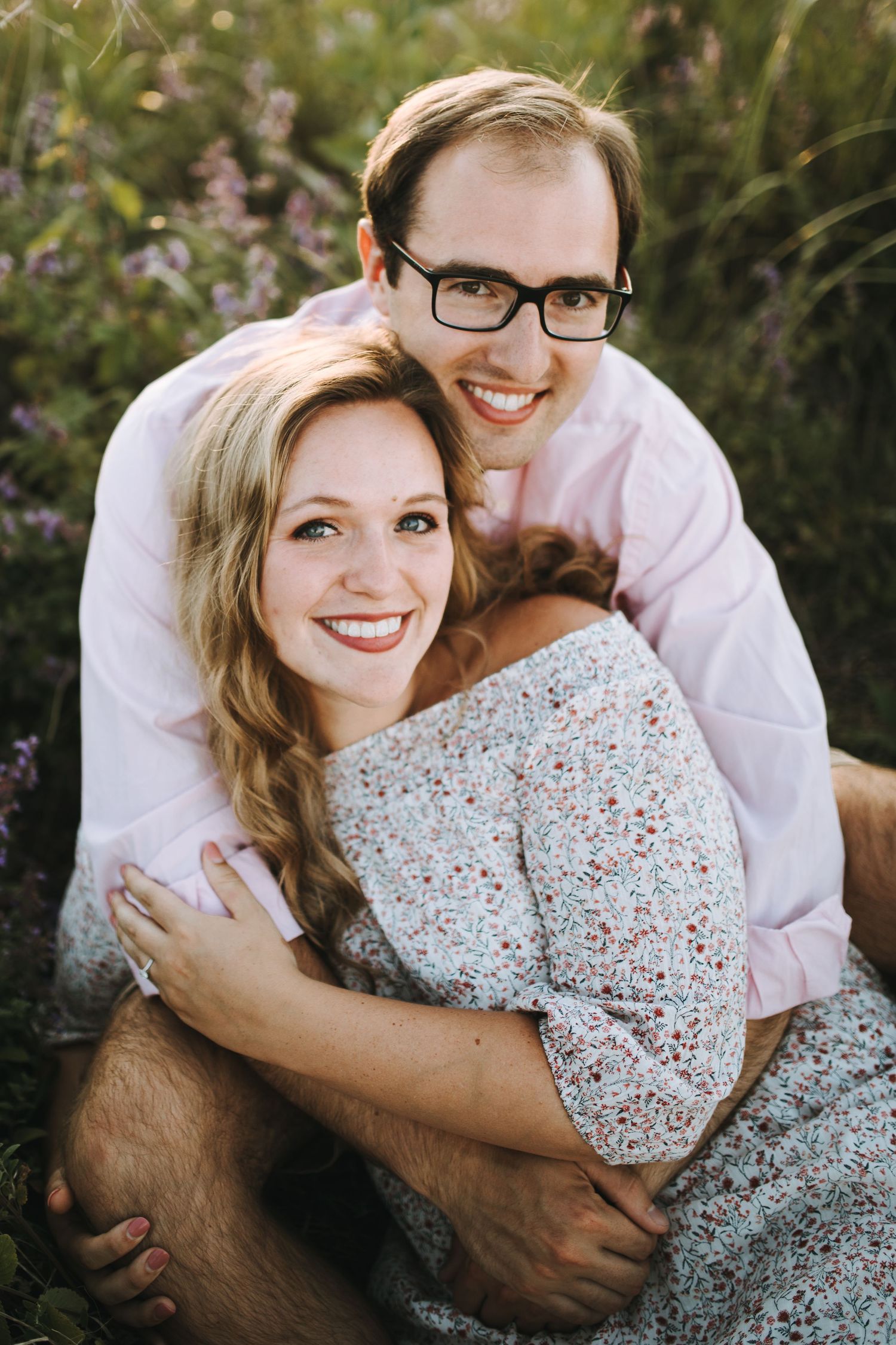 Couple embracing on grass during outdoor photo session.