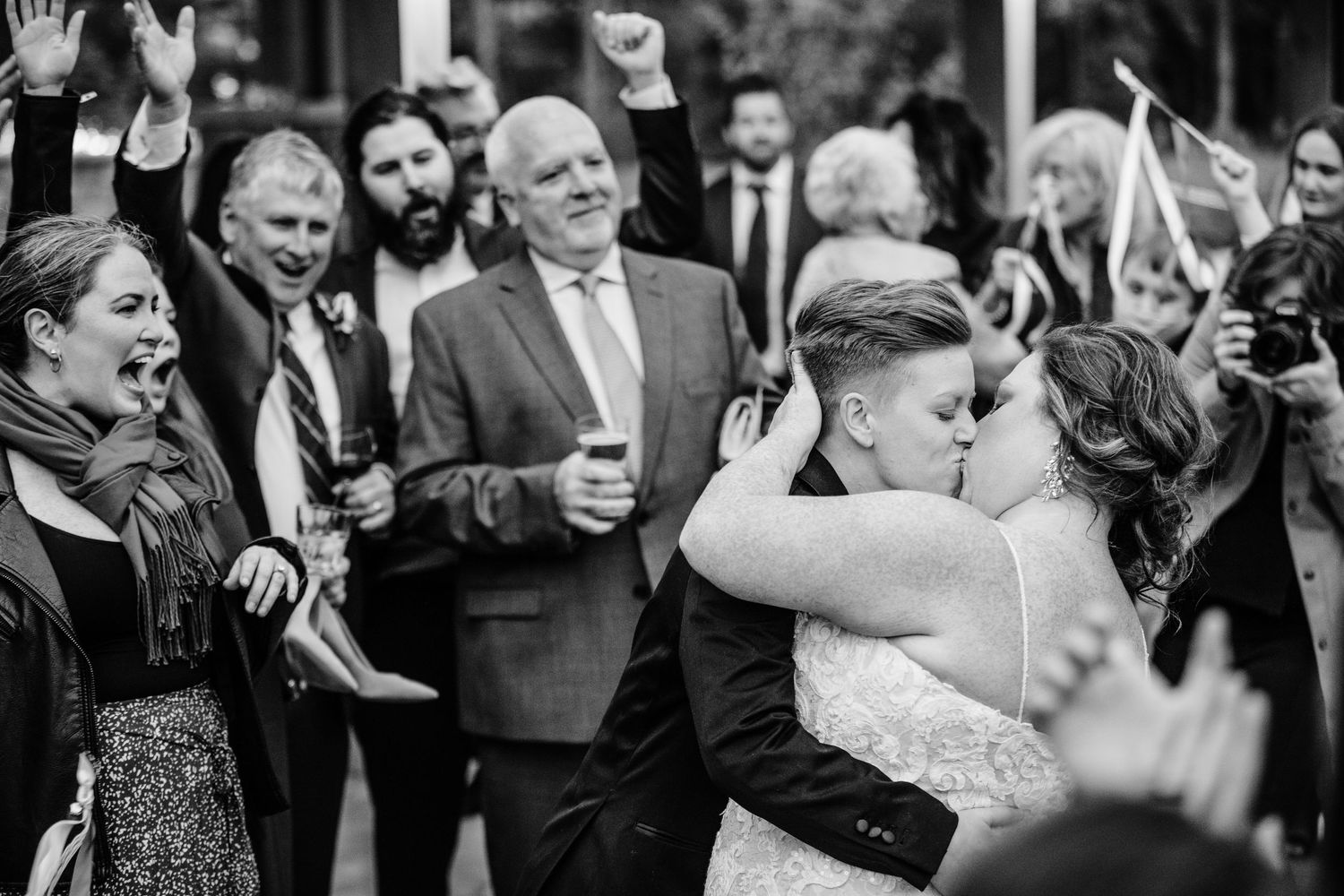 Black and white photo of wedding guests celebrating and dancing at a joyous reception party.