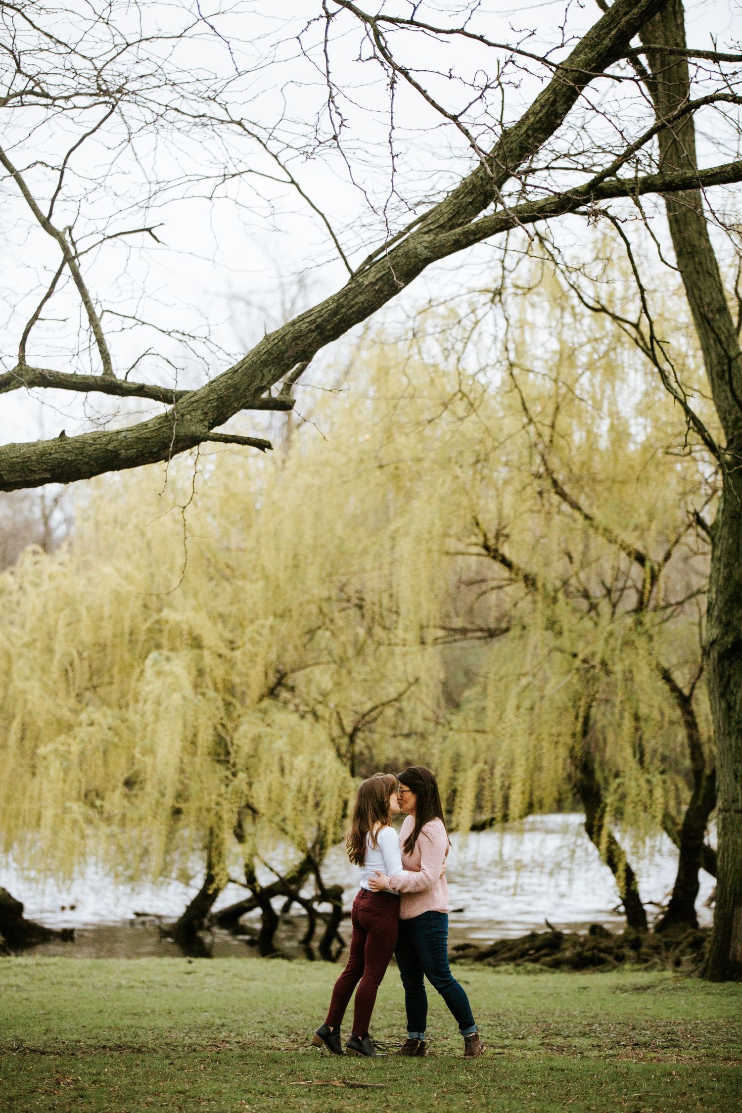 A romantic couple shares tender moments beneath willow trees by a lake in a series of connected photos.