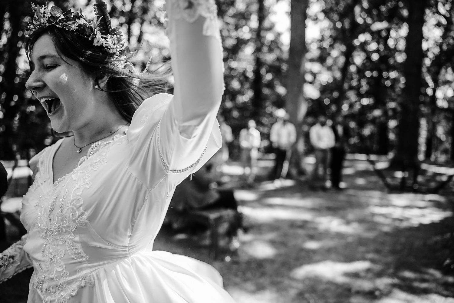 A joyful celebration moment captured in a sunlit wooded wedding setting.