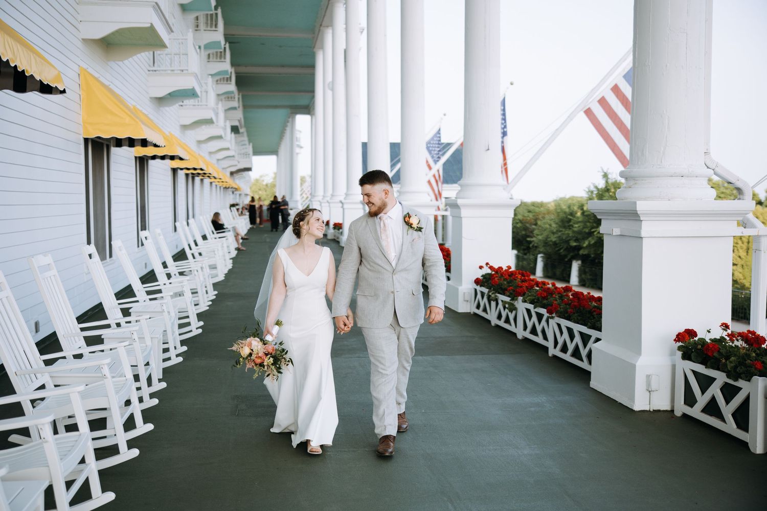 Elegant white columned porch with rocking chairs and American flags creates classic wedding venue atmosphere.