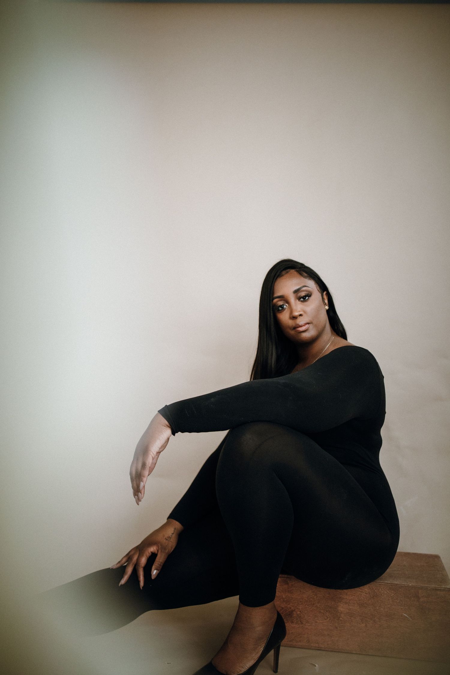 Artistic photo series showing dramatic poses in black outfit against minimalist backdrop.