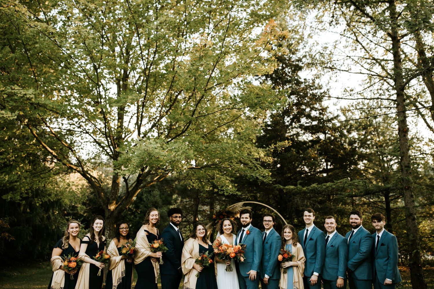 Wedding party lined up for photos in a scenic outdoor fall setting.