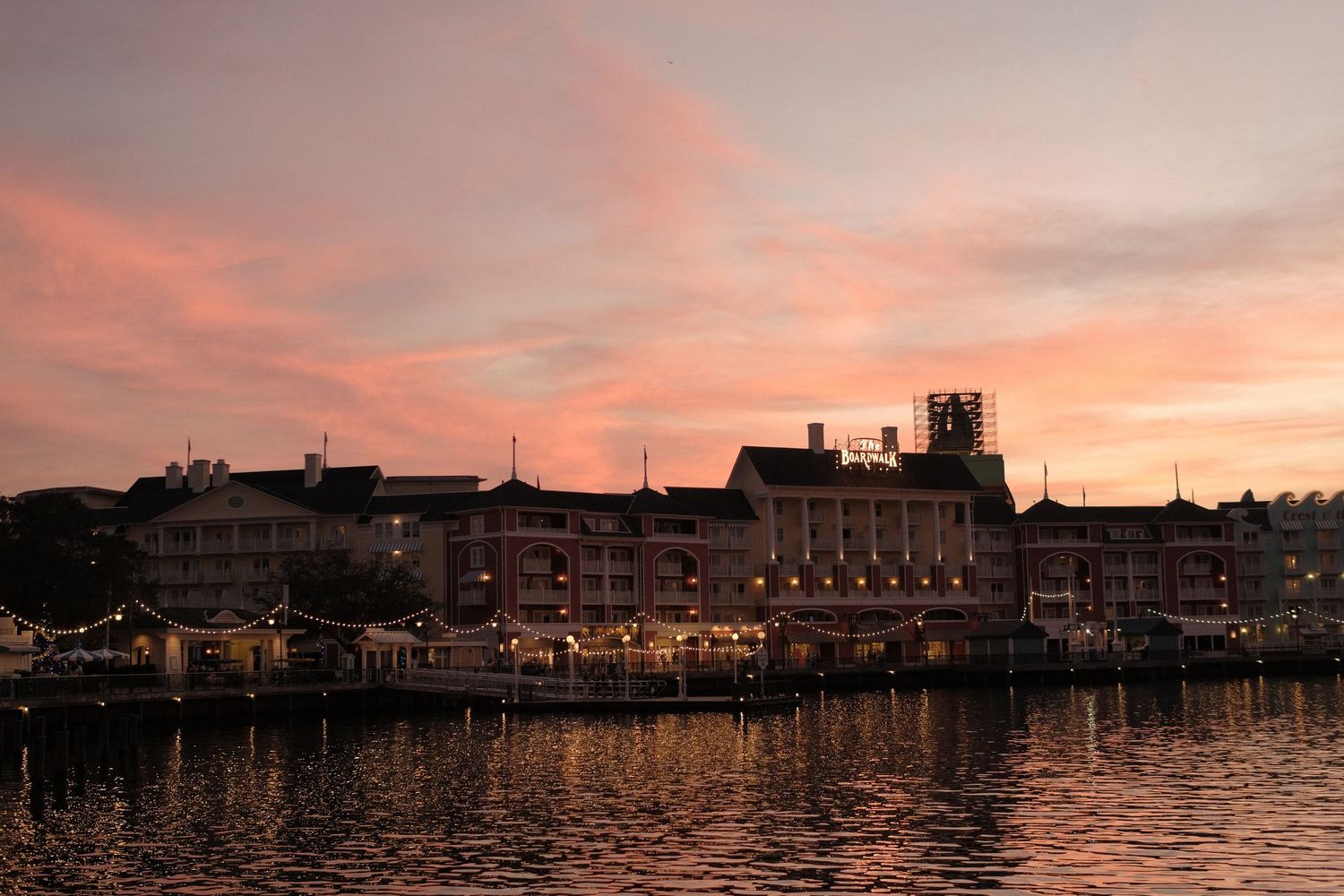 Waterfront buildings silhouetted against vibrant pink and orange sunset sky.