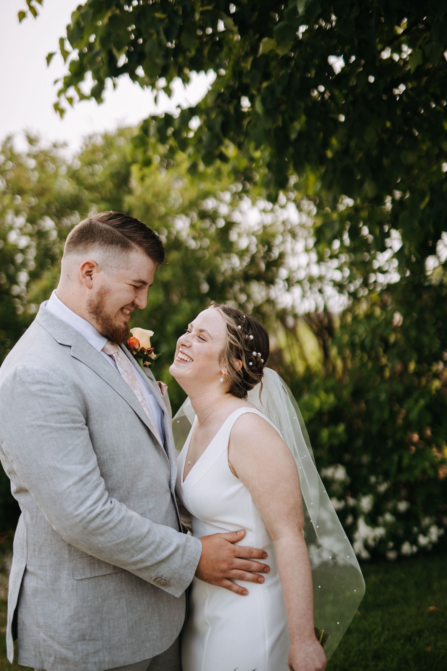 A couple shares joyful laughter during their outdoor wedding portrait session.