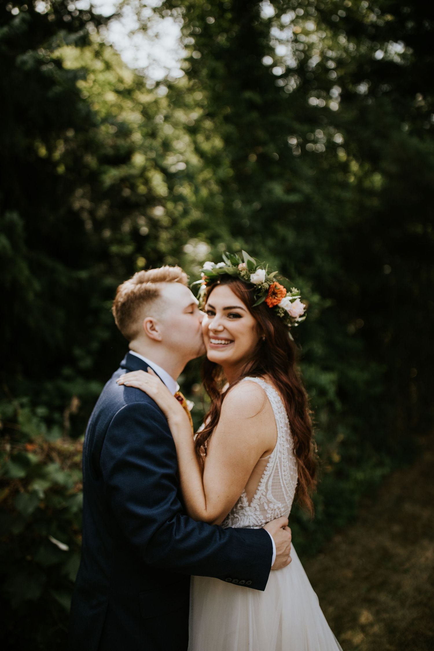 A couple shares an intimate moment in a romantic outdoor forest setting during their wedding celebration.