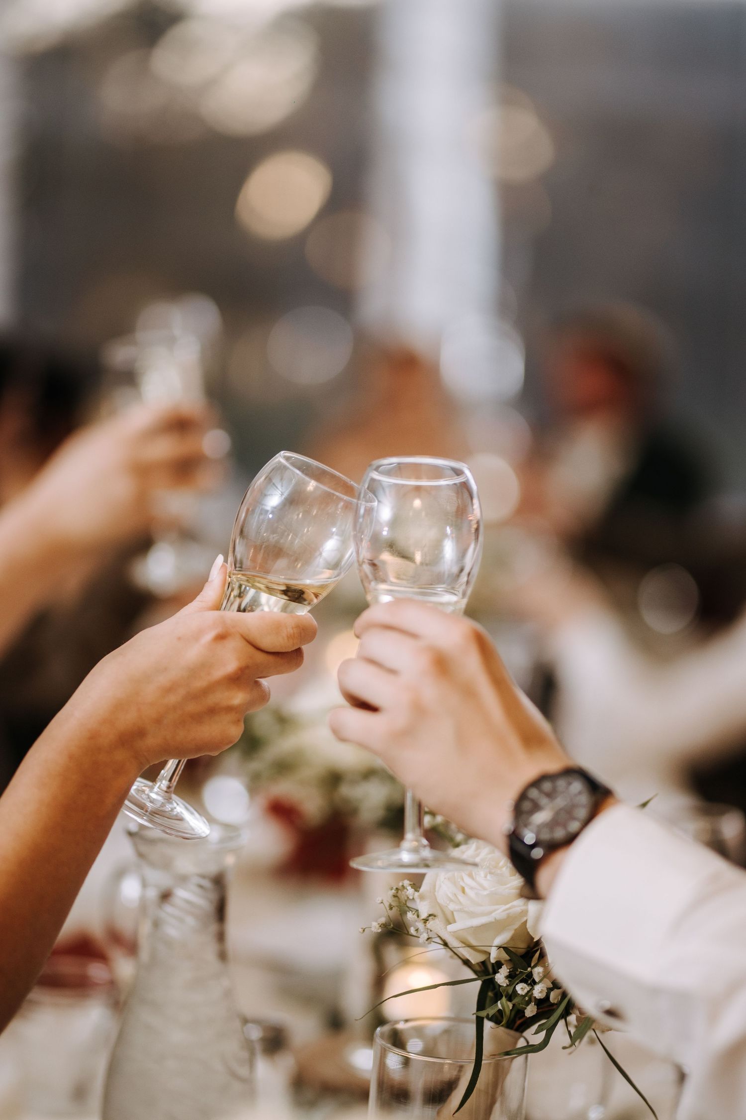 Wedding guests raising champagne glasses in a celebratory toast at an elegant reception.