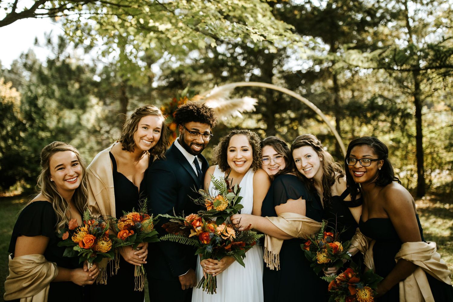 Wedding celebration with orange floral arrangements in an outdoor forest setting.