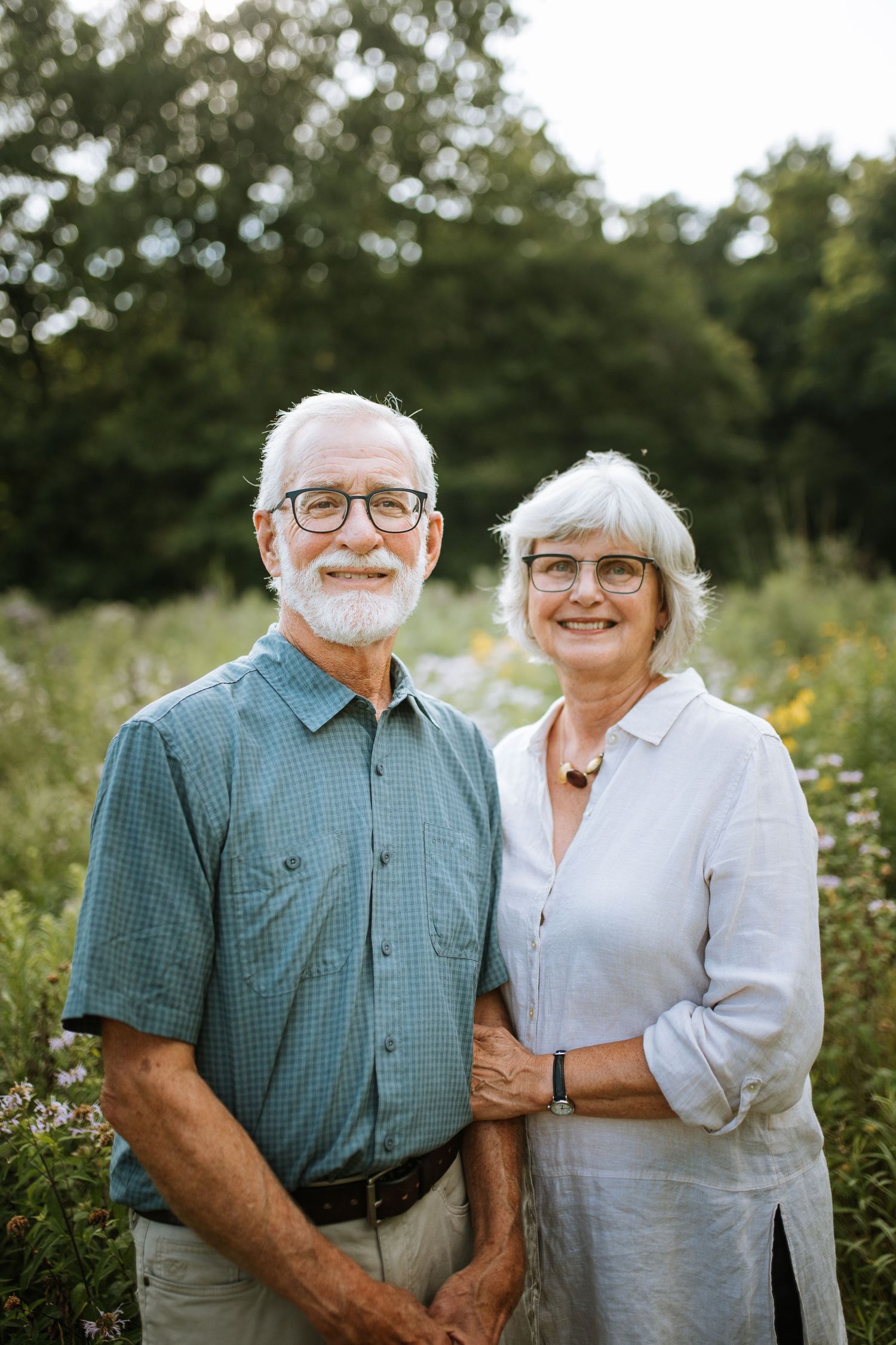 Elderly couple sharing a sweet moment together outdoors among wildflowers.