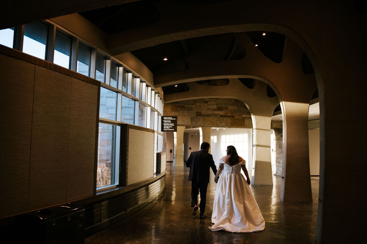 Dark corridor with backlit figures creates dramatic wedding scene silhouettes.