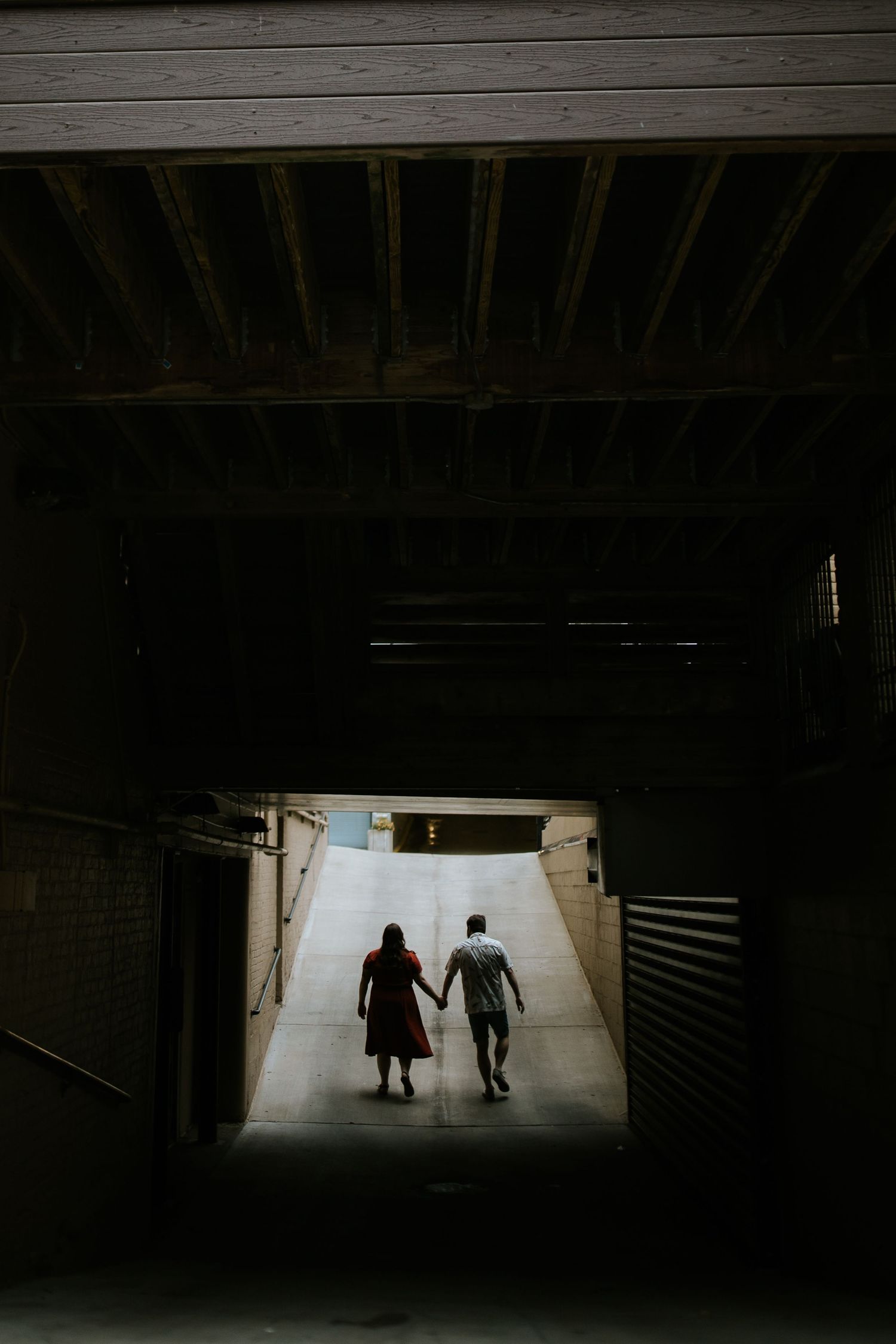 Silhouetted figures walk through dark tunnel towards bright exit.