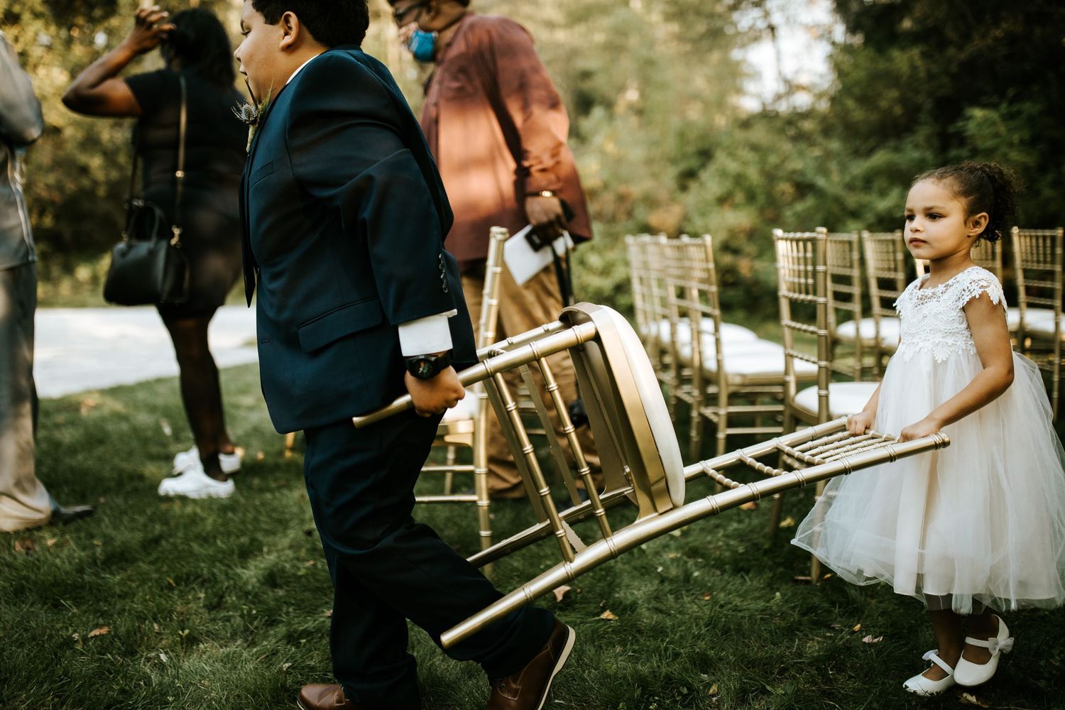 Wedding guests seated in wooden chairs during an outdoor autumn ceremony.