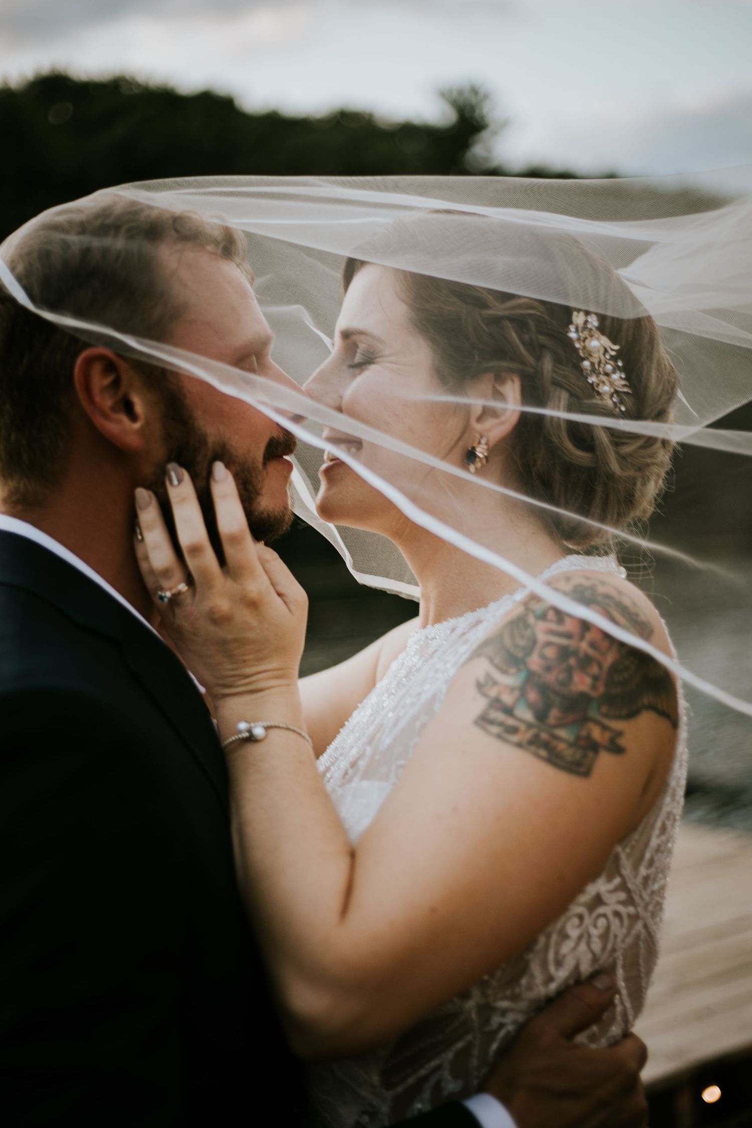Romantic moment under flowing white veil during wedding photoshoot.