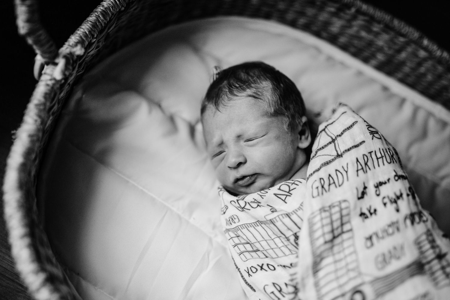 A collage of black and white photos showing a sleeping baby wrapped in a patterned blanket.