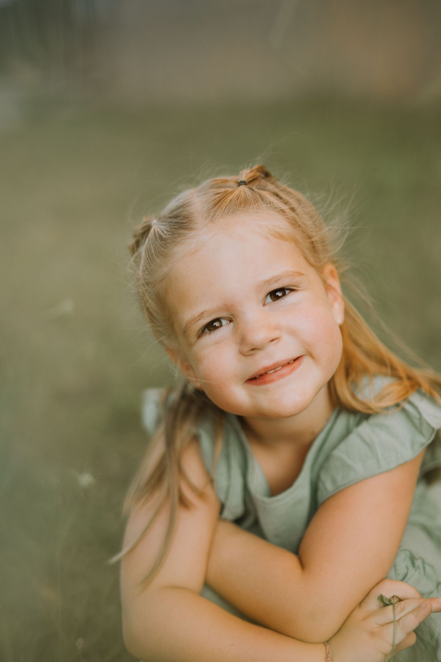 Young child lying on grass with playful expressions in natural lighting.