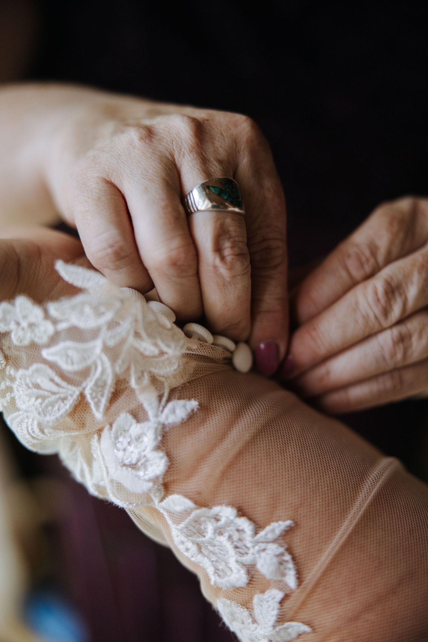 Delicate hands working with intricate lace details on wedding attire.
