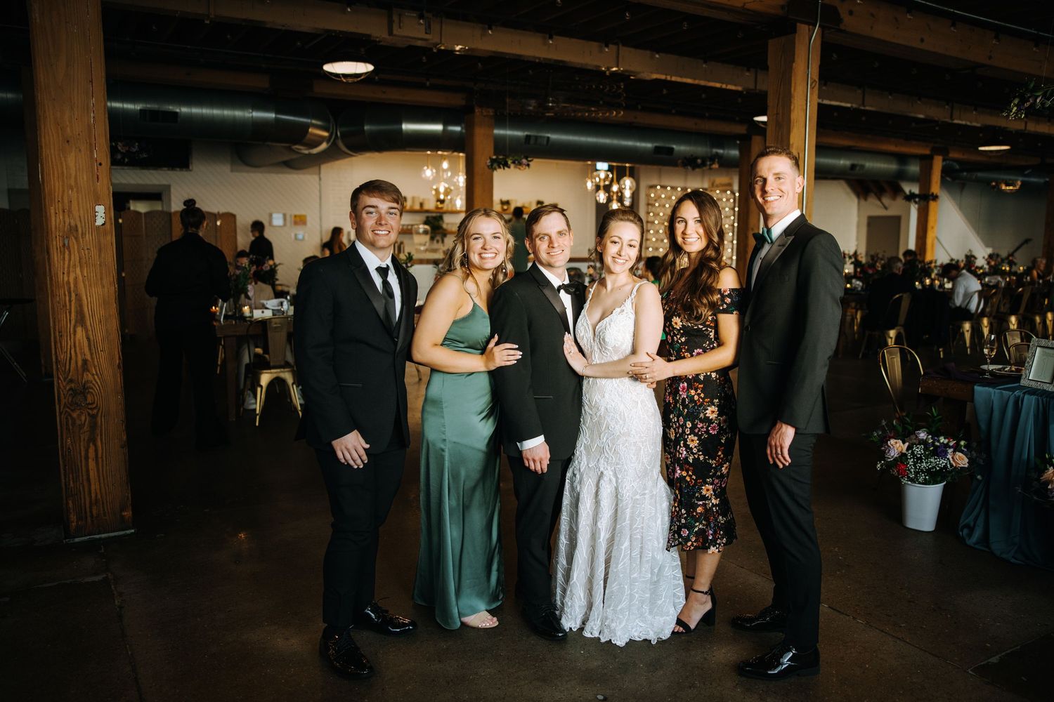 Group photo at wedding reception in industrial venue space.