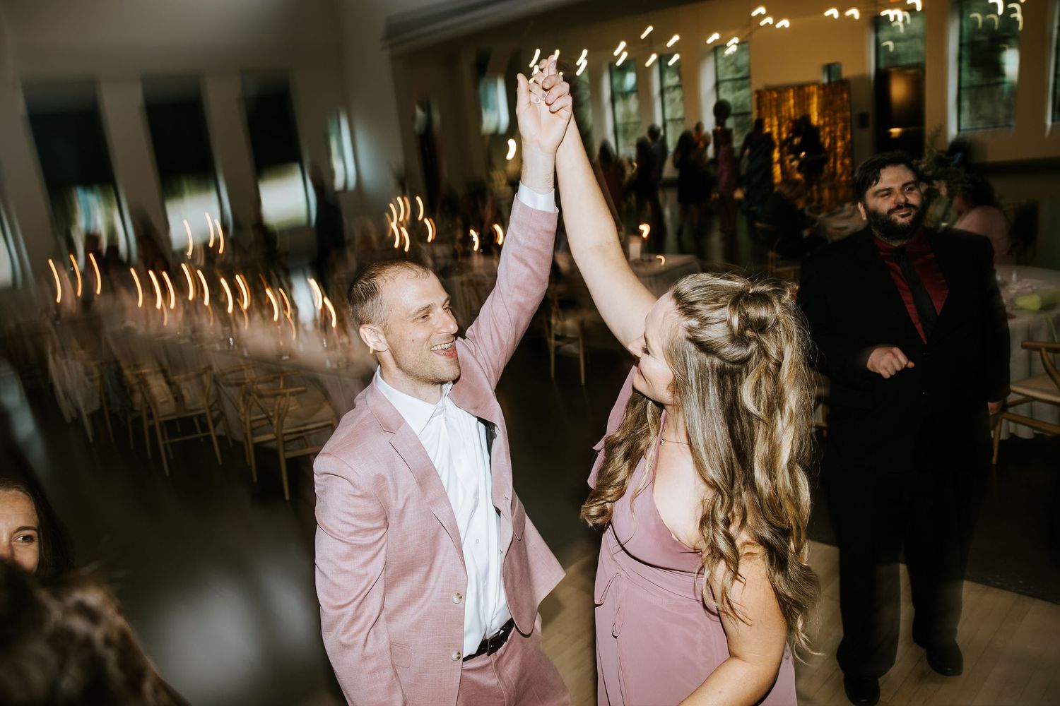 Wedding guests dancing and celebrating at evening reception party.