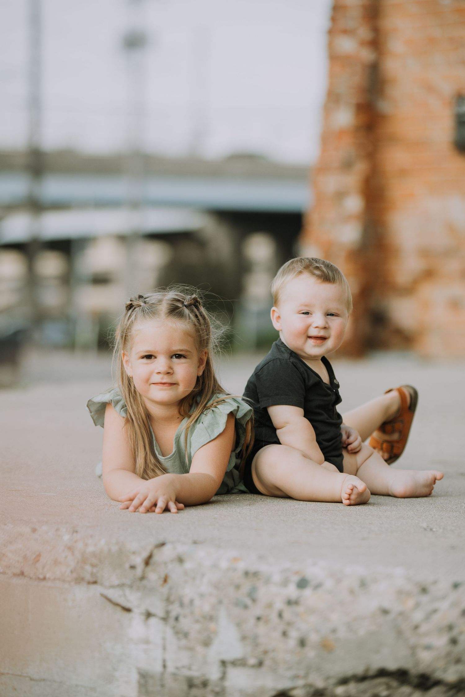 Child lying on concrete surface with playful expressions.