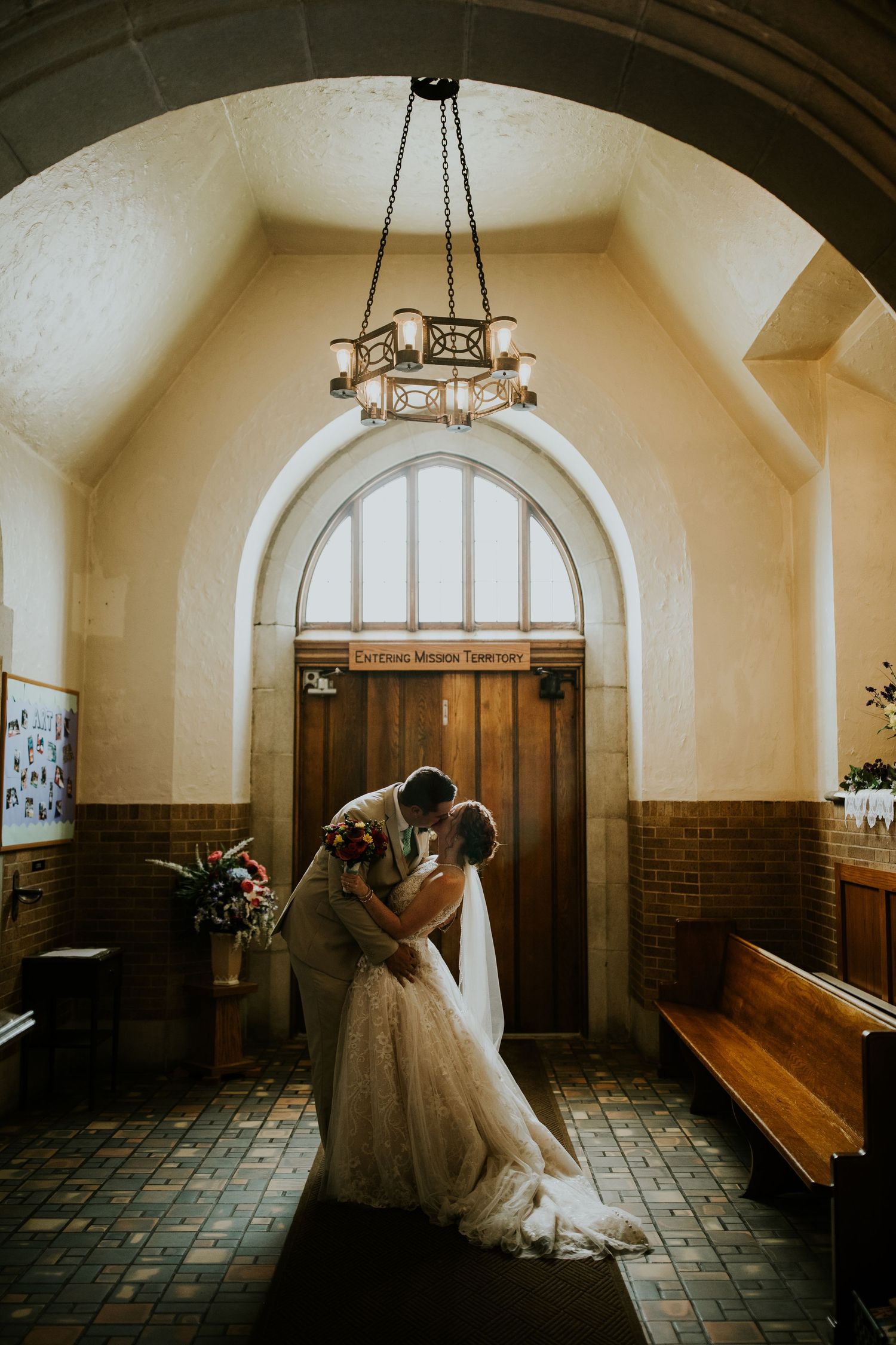 Artistic wedding photos in a vintage church hallway with arched ceilings and dramatic lighting.