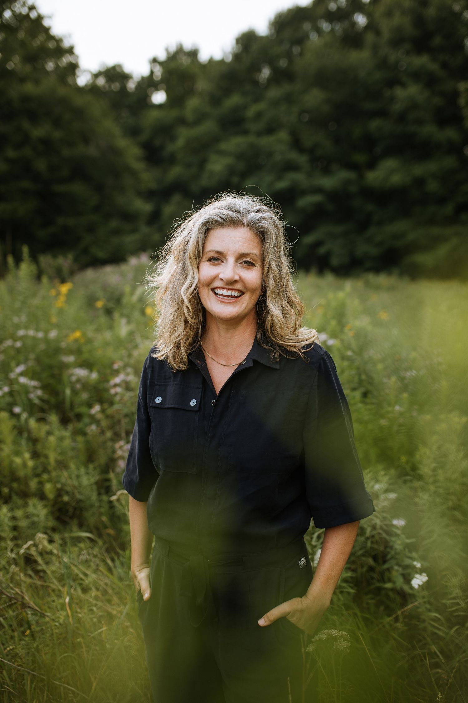 Summer portrait in a wildflower meadow with natural lighting and green backdrop.