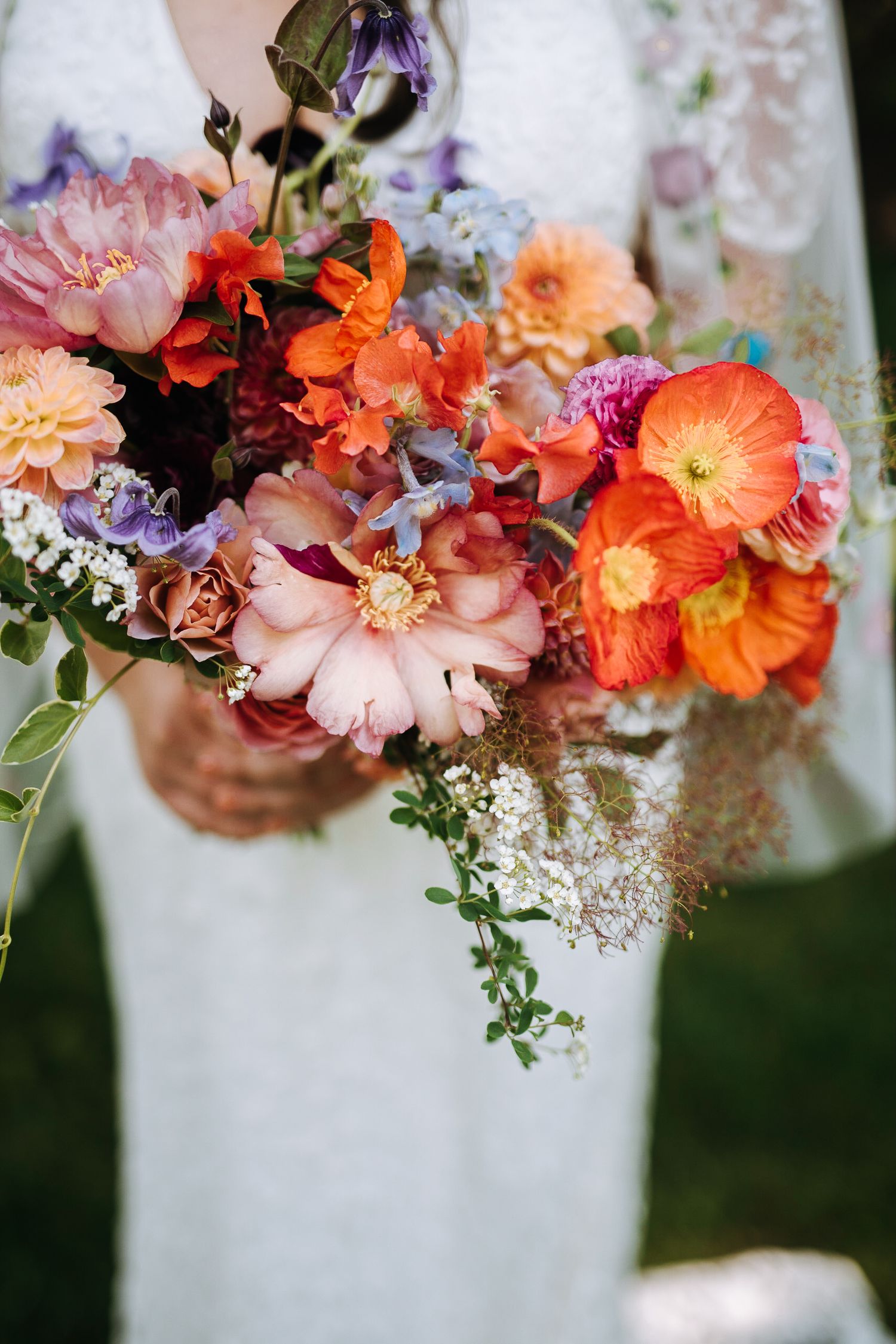 Stunning bridal bouquet featuring orange, pink, and purple flowers with delicate greenery.