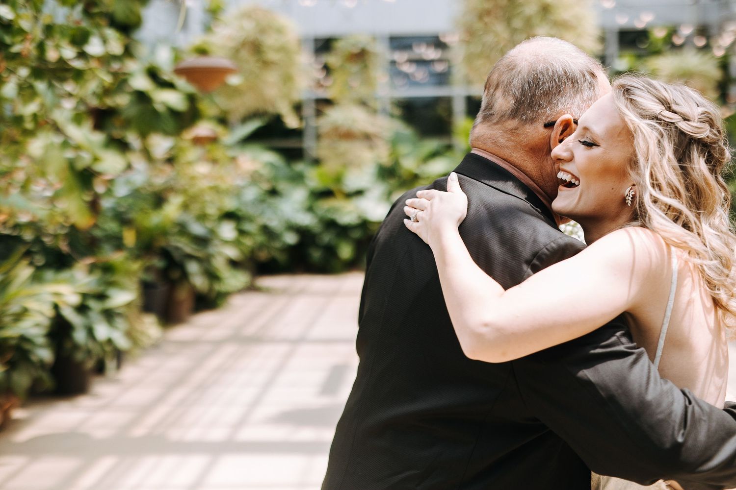 Couple sharing intimate dance moment in sunlit garden setting.