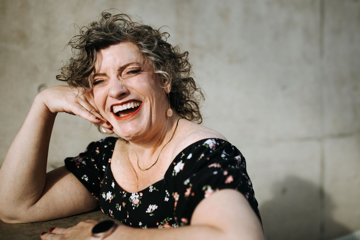 Lifestyle portraits showing genuine laughter and happiness against a concrete wall.