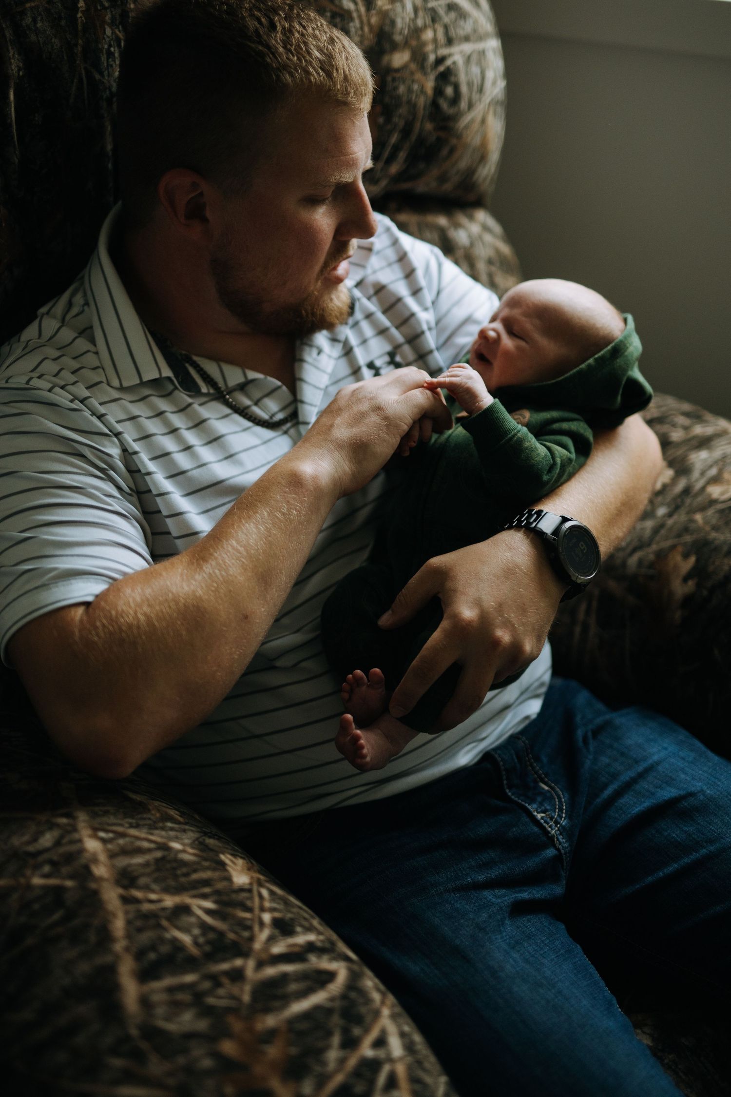 Tender moment between parent and child on patterned couch in dim lighting.