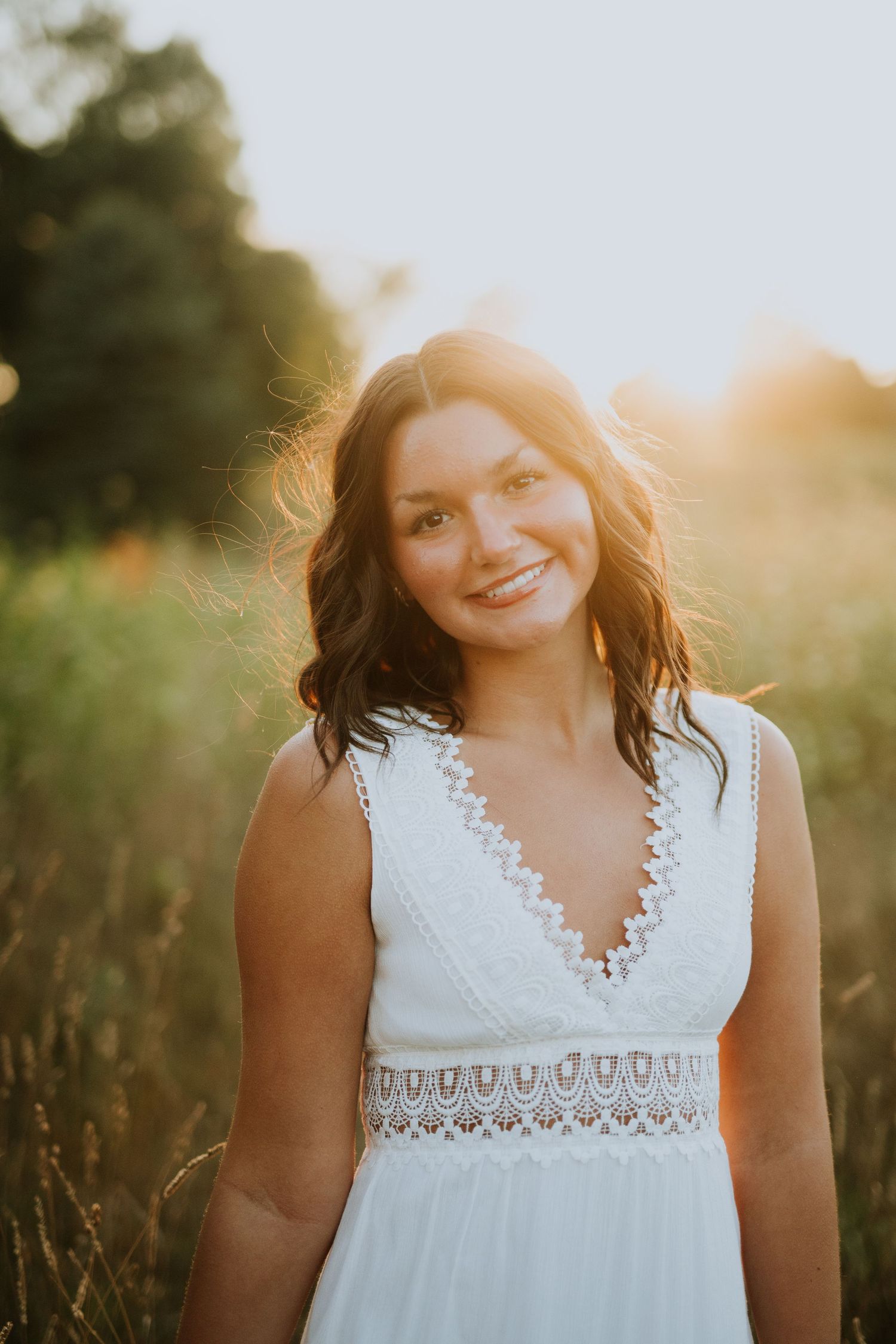 A white lace dress glows in warm evening sunlight amidst a natural outdoor setting.