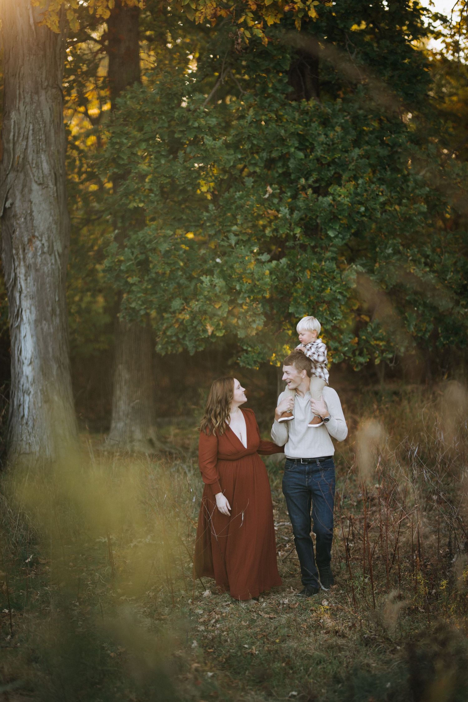 A family shares a tender moment in a golden-lit forest clearing during autumn.