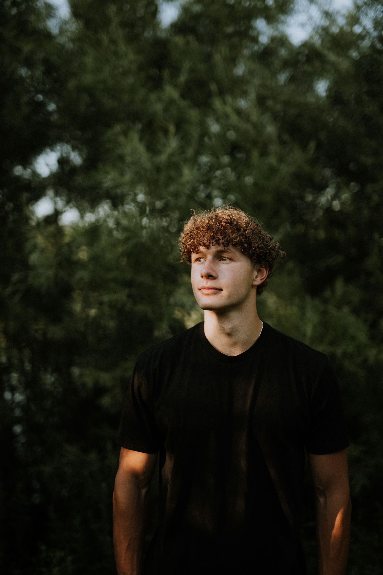 Side profile portrait against natural green foliage background.