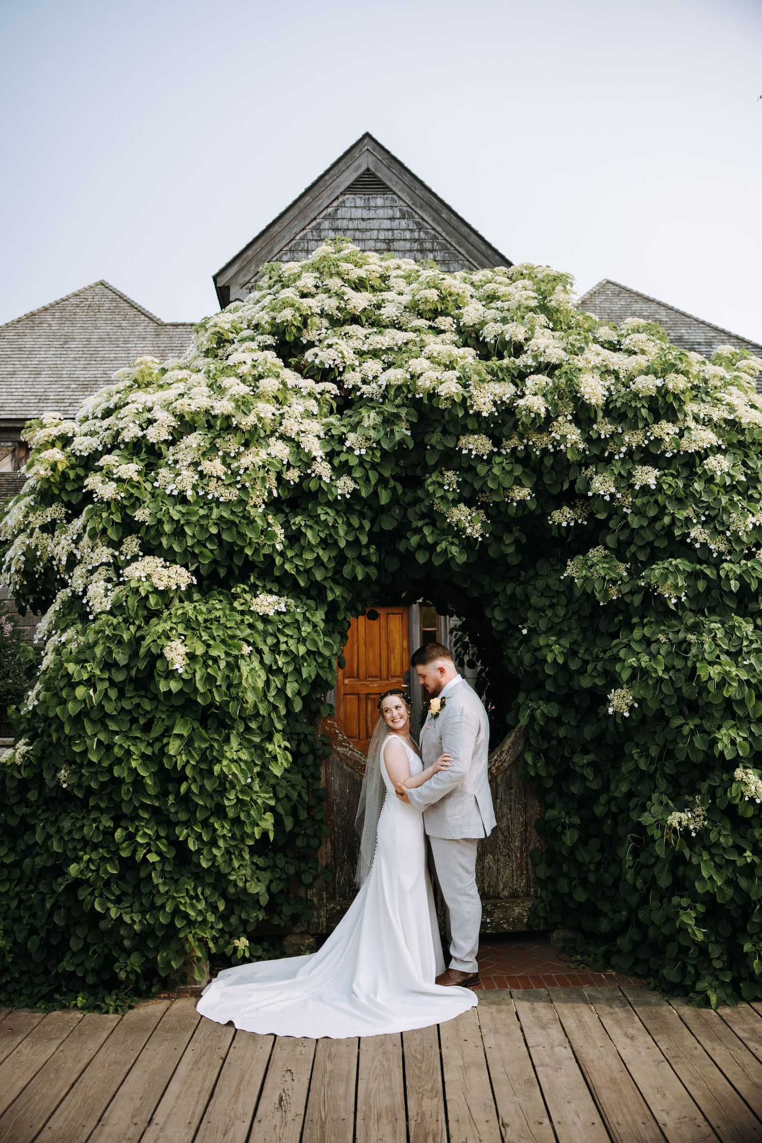 A romantic moment captured on a wooden deck beneath flowering vines.