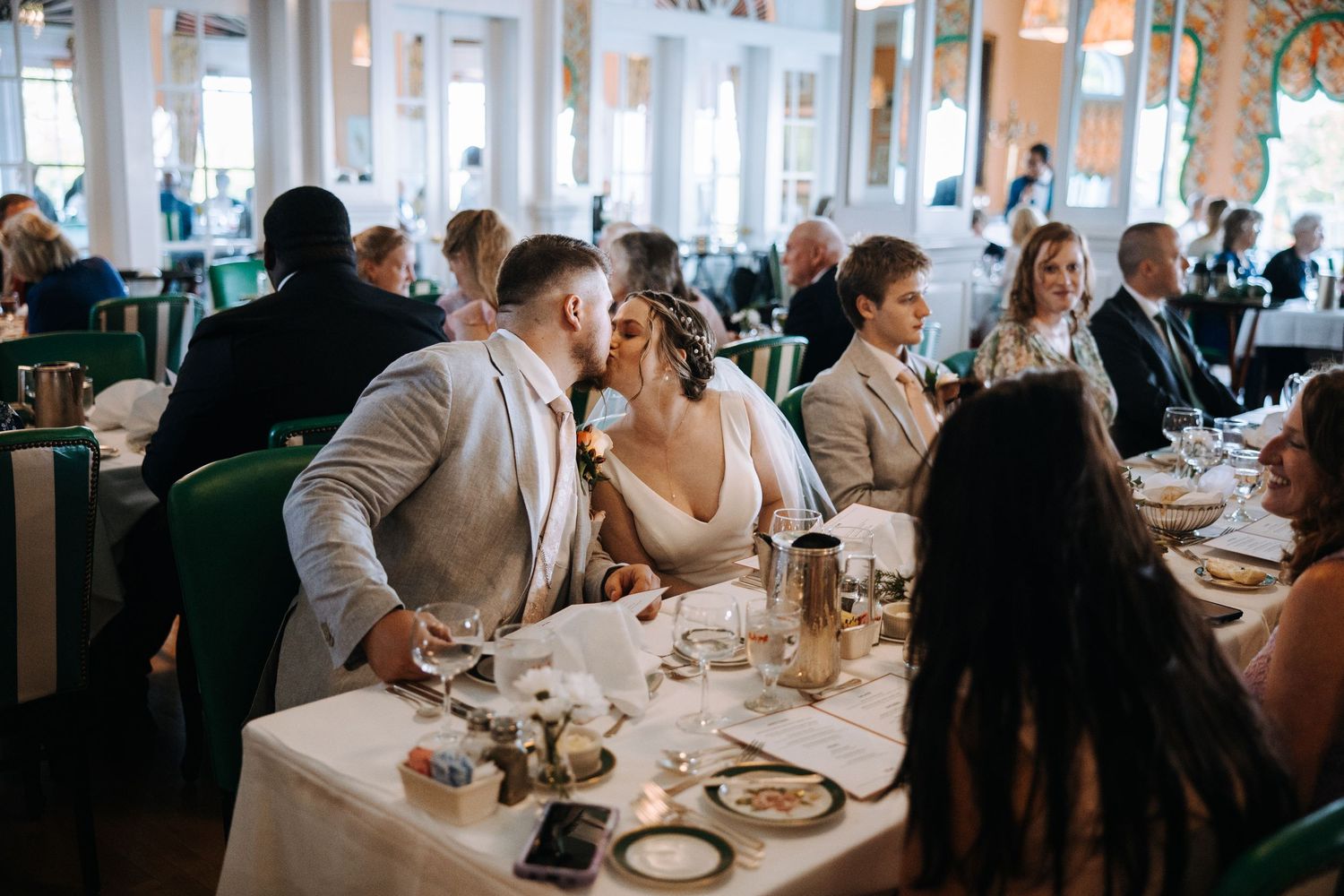 Wedding reception dining room with natural light streaming through large windows.