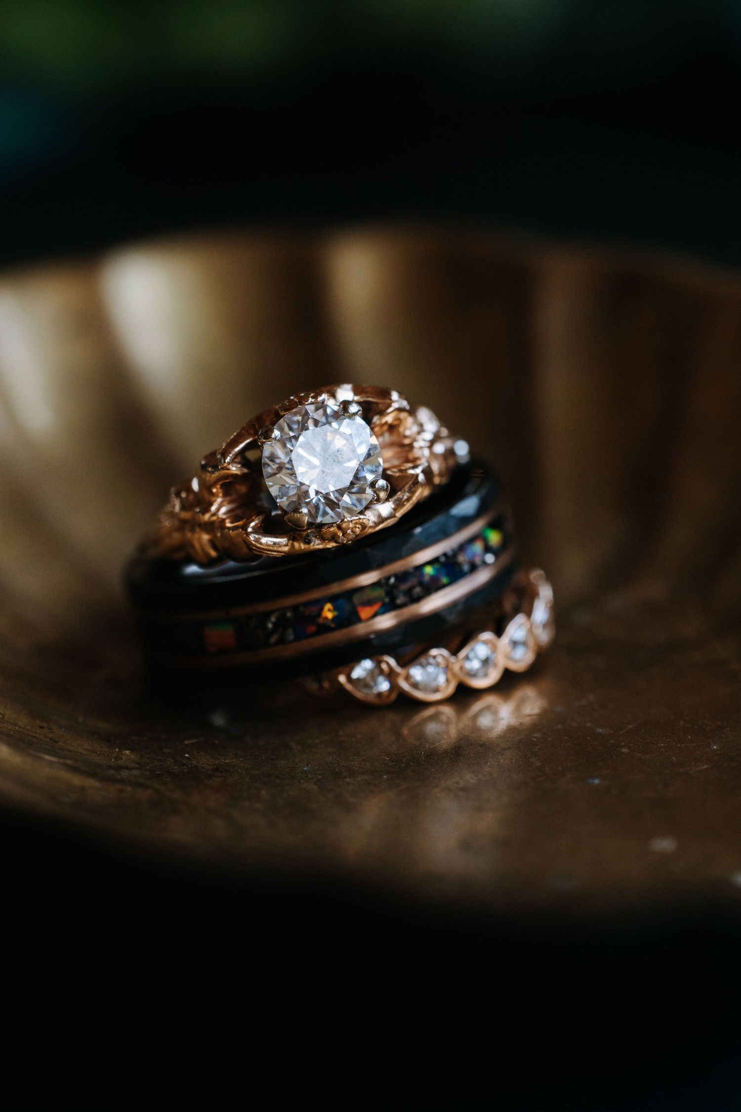 Three elegant wedding rings with diamonds stacked together on a dark reflective surface.