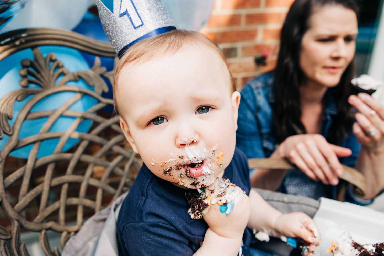 a baby boy celebrates his first birthday with a party hat and cake
