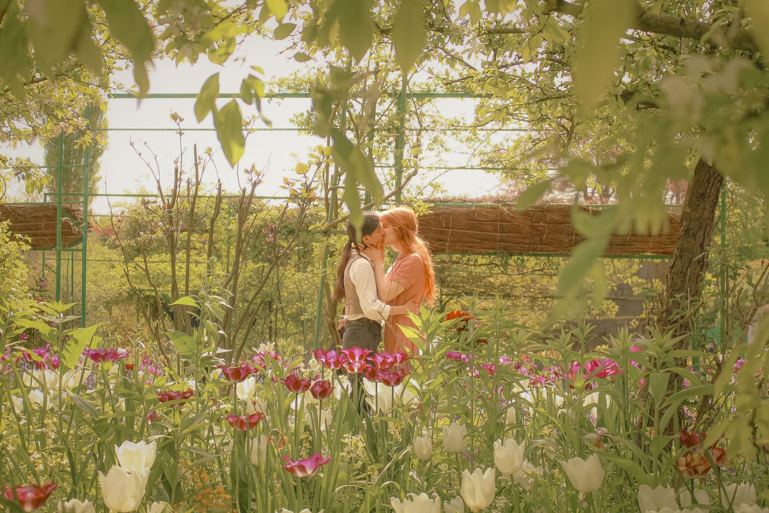 A couple is kissing surround by plants and flowers in spring in Giverny, at Monet's garden.