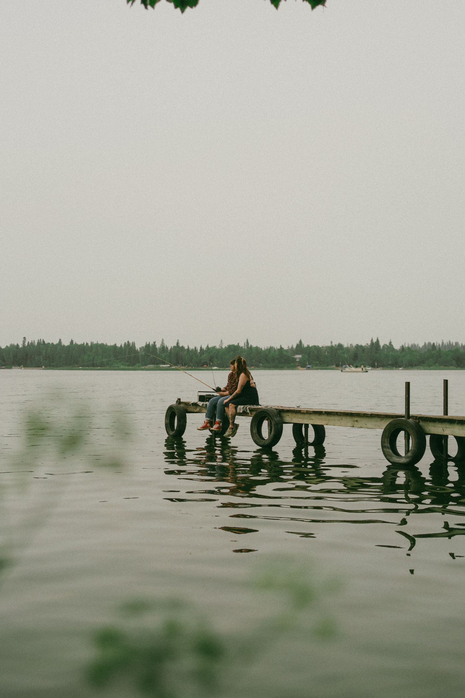A photo of an LGBTQ couple on the dock at the lake. Candid and cinematic.