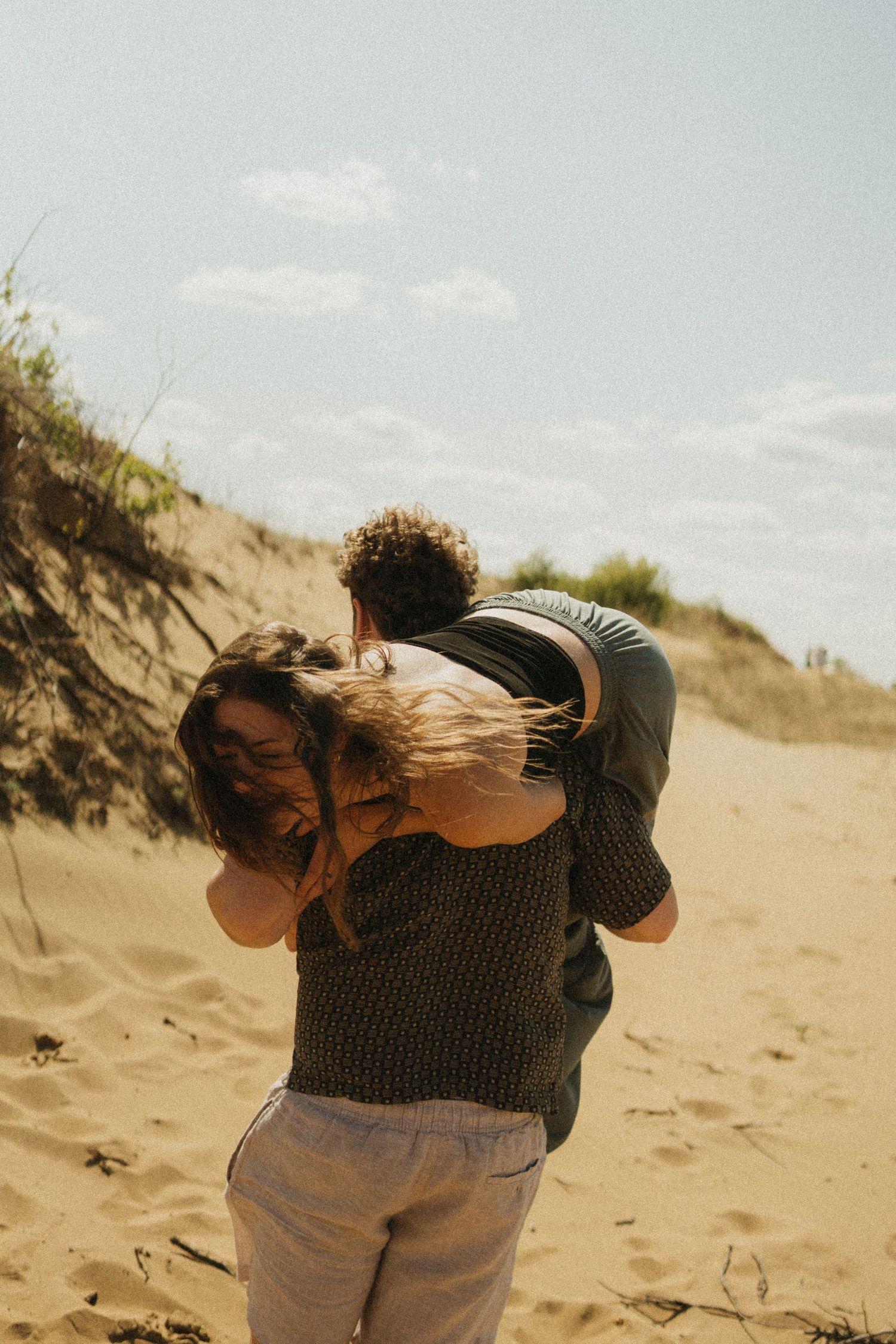 a man throws his girlfriend over his shoulder and she laughs
