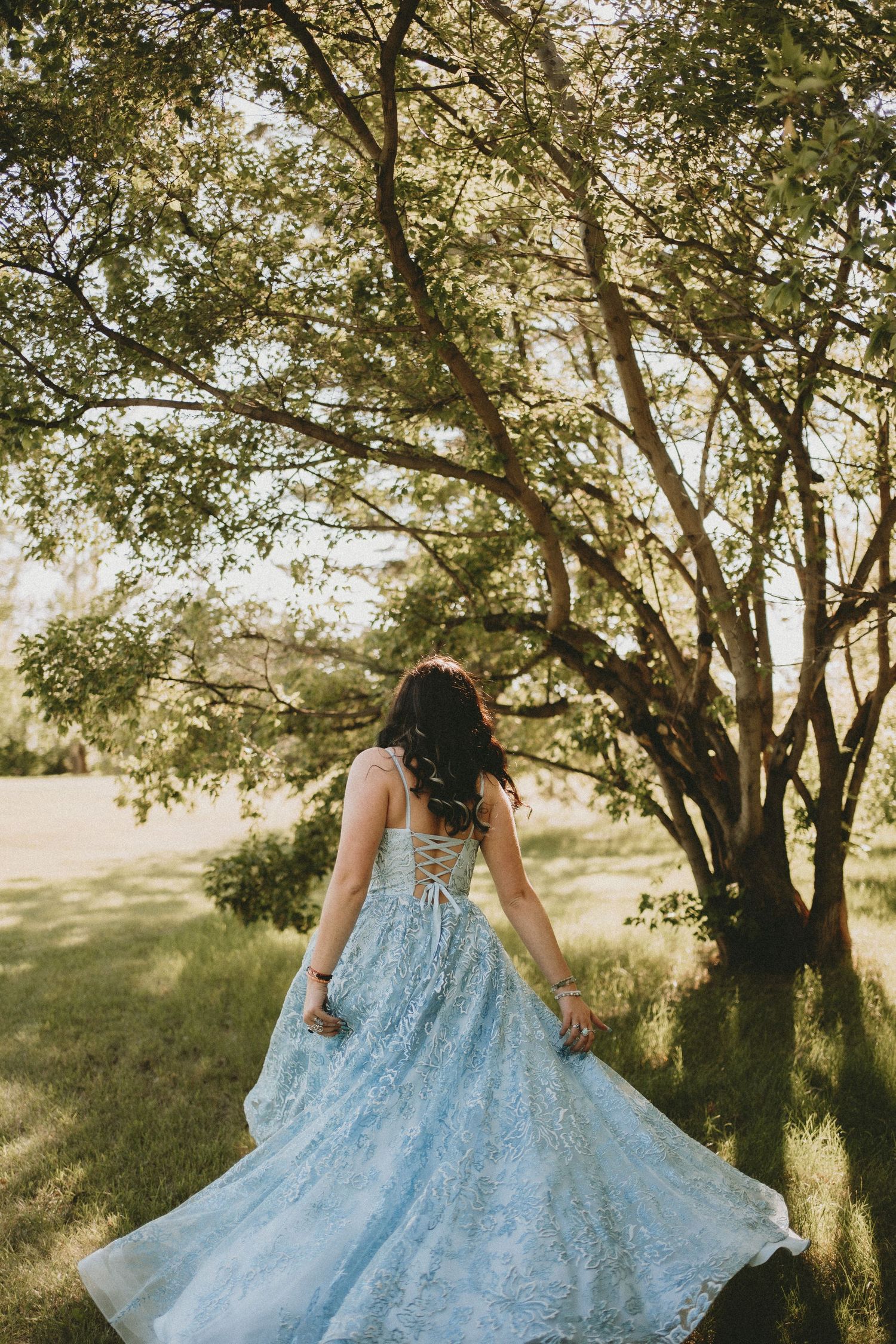 a graduate twirls in the sunset in a blue gown