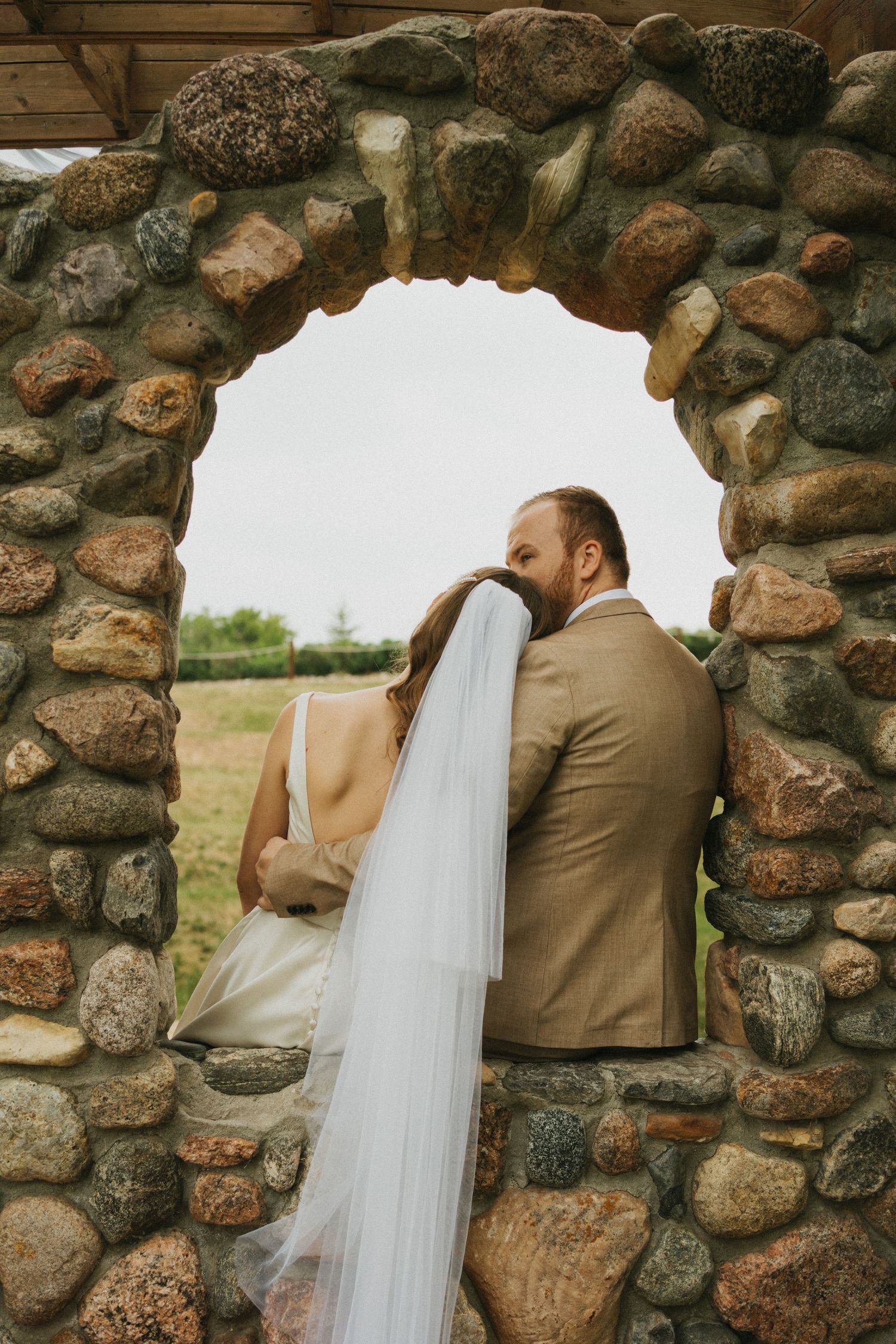 A photo of a bride and groom in a castle like setting. The veil blows in the wind.